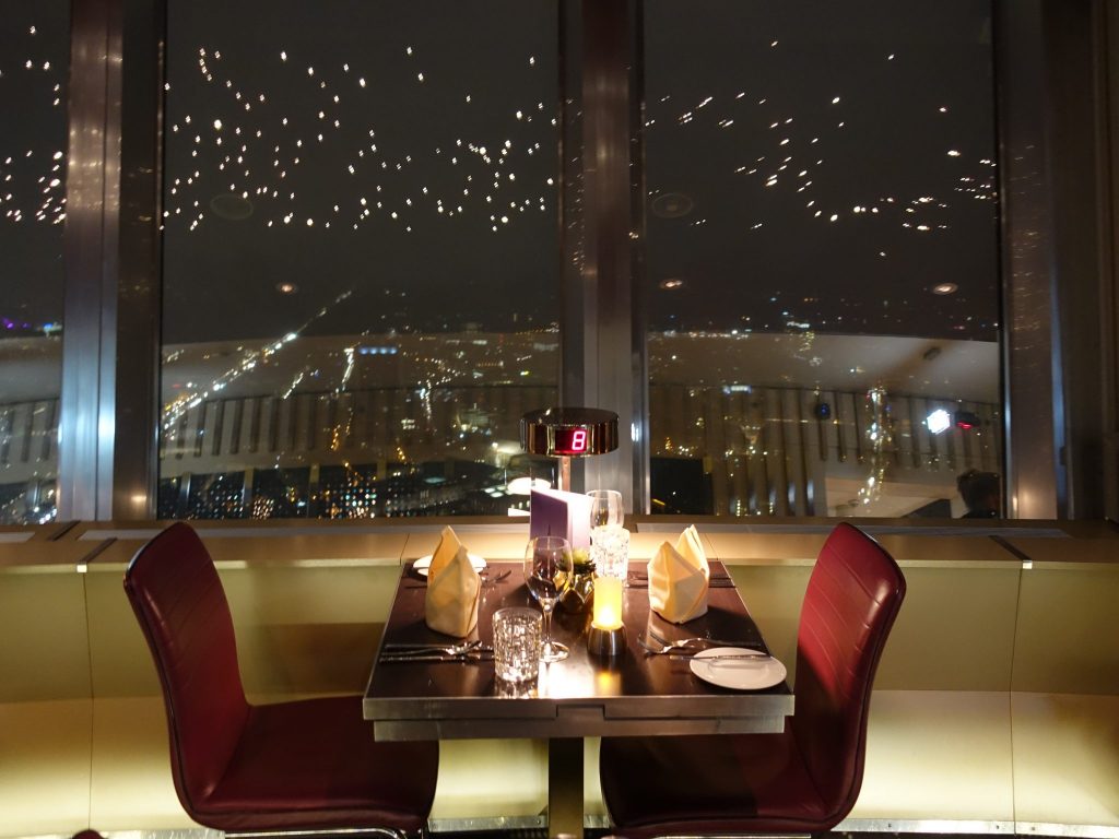 Ein 2er Tisch mit roten Stühlen am Fenster des Fernsehturms im Restaurant Sphere in Berlin