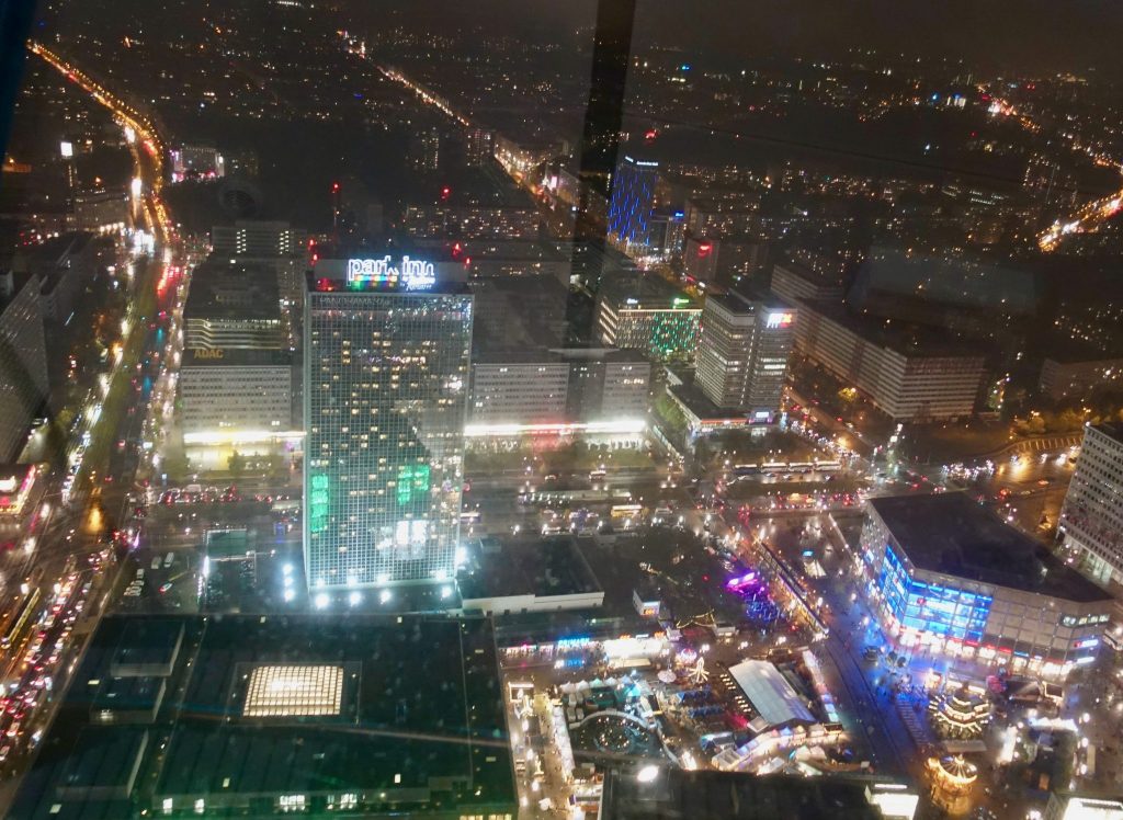 Aussicht bei Nacht vom Berliner Fernsehturm auf die hell erleuchteten Gebäude und Straße der Stadt