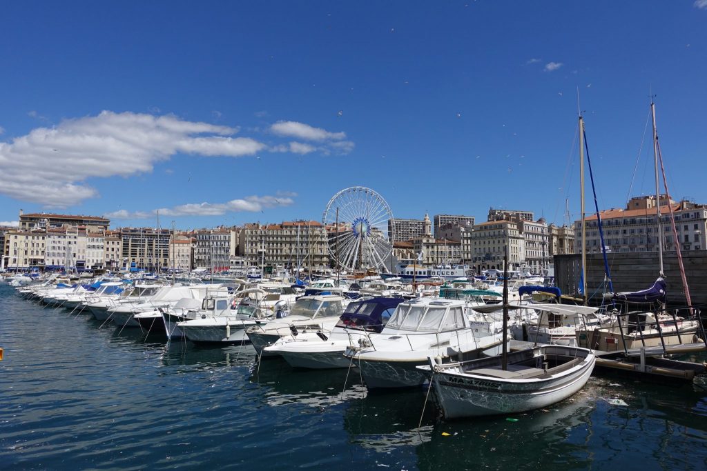 Unzählige Boote liegen im alten Hafen von Mareille, dahinter sind Häuser und ein Riesenrad zu sehen
