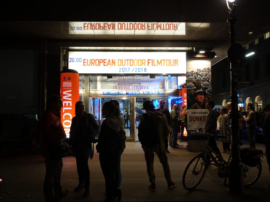 Der beleuchtete Eingang mit der Beschriftung "European Outdoor Filmtour" beim Gartenbaukino im Wien bei Dunkelheit