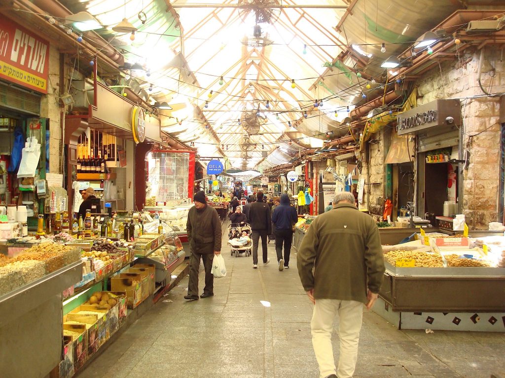 Durchgang in einem Markt, links und rechts die Stände, dazwischen ein paar Menschen, die durch den Markt hindurchschlendern