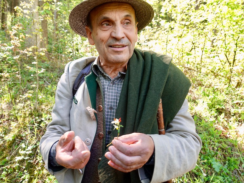 Fritz Wolf beim Erklären mit Hut und Blume in der Hand